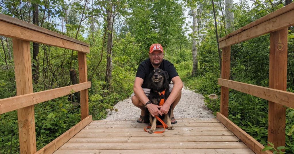 man holding his dog on bridge | Tips and Tricks for Hiking with Dogs