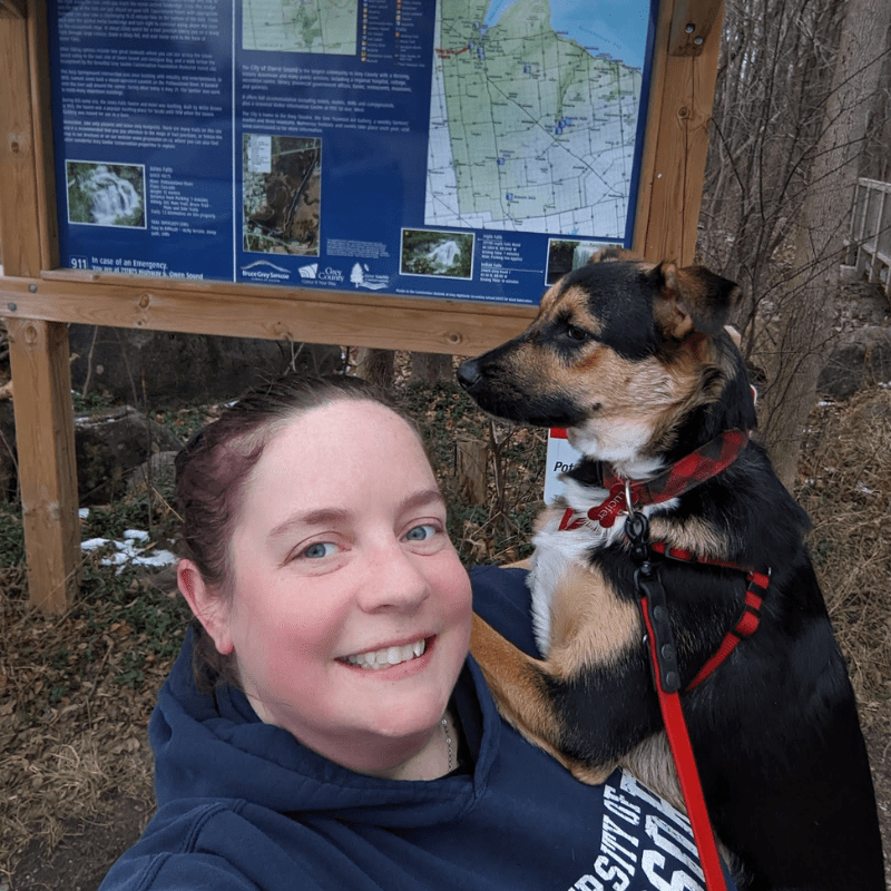 woman holding a dog at a trailhead