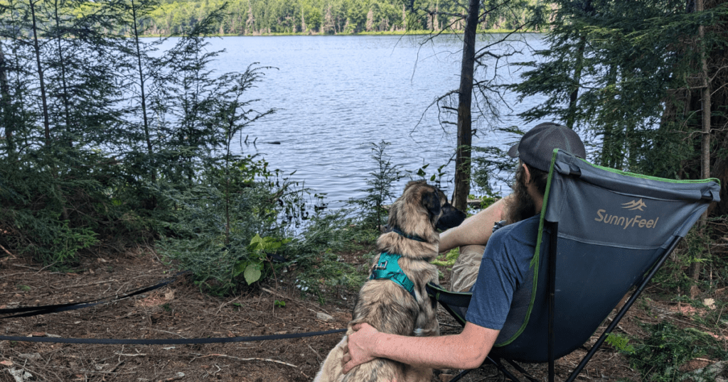 man sitting next to a dog looking out at the lake | Limberlost Forest & Wildlife Reserve: Video Review