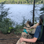 man sitting next to a dog looking out at the lake | Limberlost Forest & Wildlife Reserve: Video Review