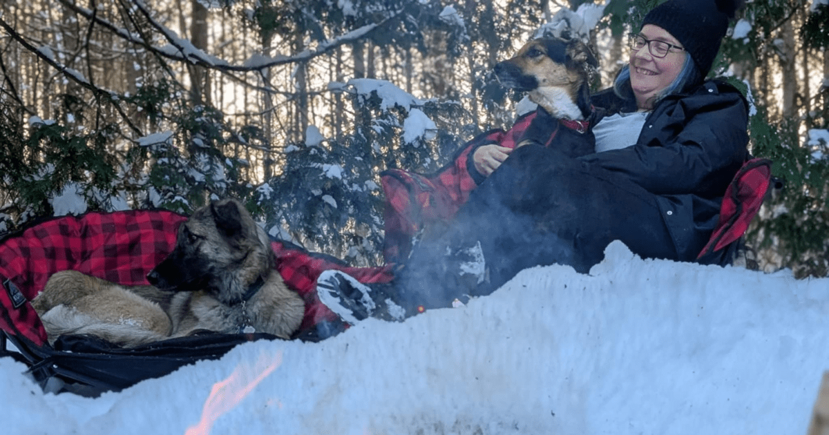a woman and two dogs sitting around a winter fire in kuma lazy bear chairs | 2024 Holiday Gift Guide for Adventure-Loving Dogs and Cats