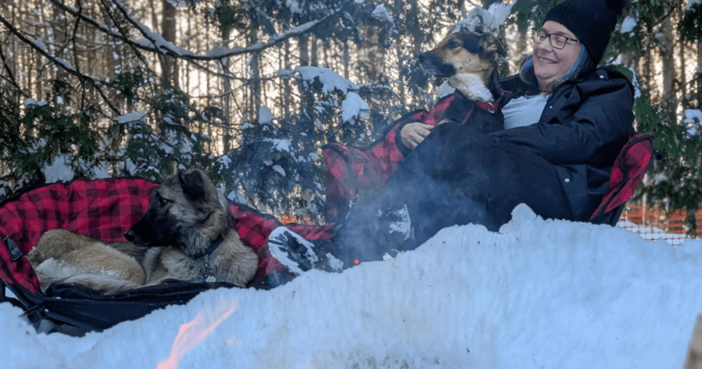 two dogs and a woman sitting around a winter fire in kuma lazy bear chairs | 2024 Holiday Gift Guide for Adventure-Loving Dogs and Cats