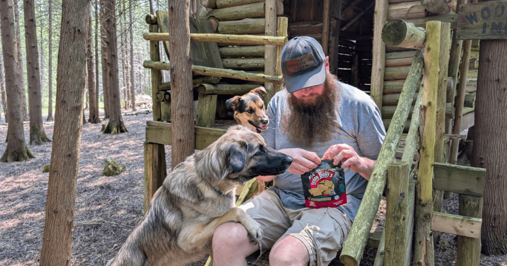 a man opening a bag of dog treats for two dogs | Tested & Trusted: The Canadian Pet and Outdoor Brands That Make Our Trips Possible